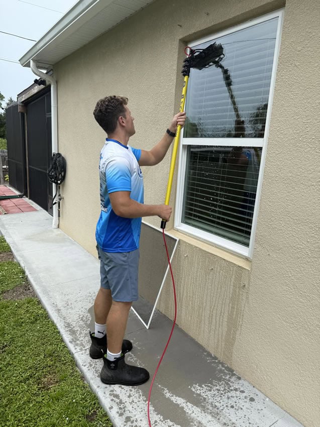 Window Cleaning in Brevard County Florida Jake from Bluwave powerwashing cleaning a window with a water fed pole